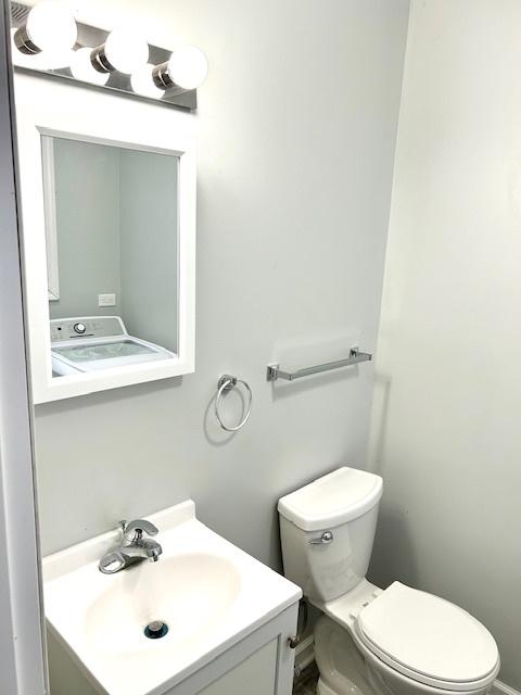 bathroom featuring vanity, toilet, and washer / clothes dryer