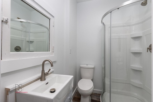 bathroom with hardwood / wood-style floors, toilet, walk in shower, and sink