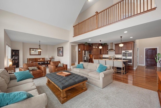 living room featuring hardwood / wood-style floors, high vaulted ceiling, and sink