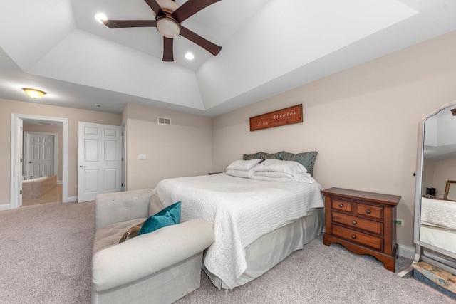 bedroom with a raised ceiling, ceiling fan, and light colored carpet