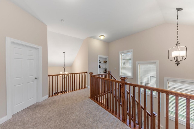 corridor featuring carpet floors, a chandelier, and lofted ceiling