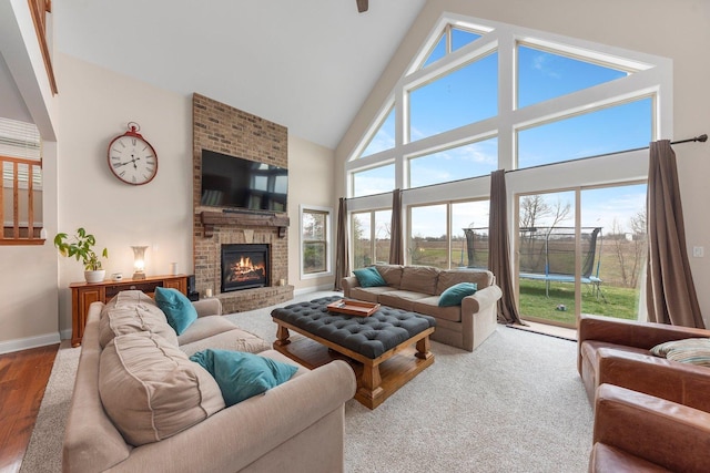 living room featuring wood-type flooring, high vaulted ceiling, and a brick fireplace