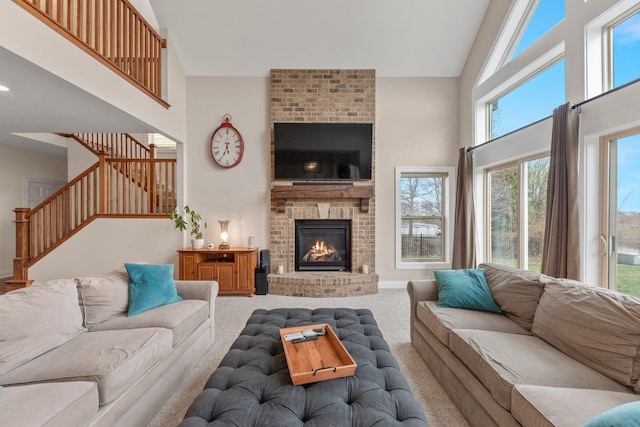 carpeted living room featuring a fireplace, high vaulted ceiling, and a healthy amount of sunlight