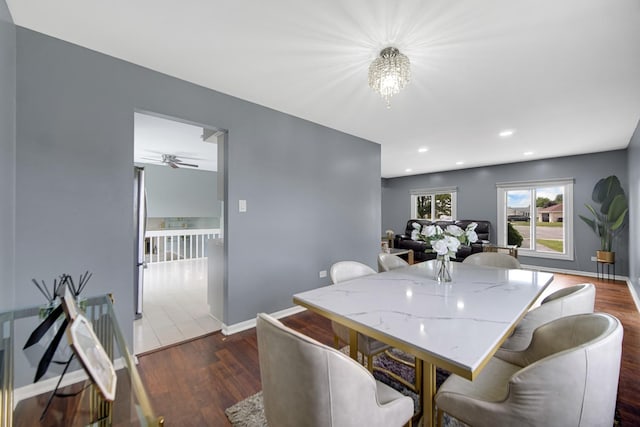 dining space with ceiling fan with notable chandelier and dark hardwood / wood-style floors