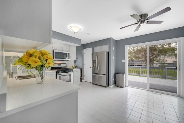 kitchen featuring white cabinets, sink, ceiling fan, appliances with stainless steel finishes, and light tile patterned flooring