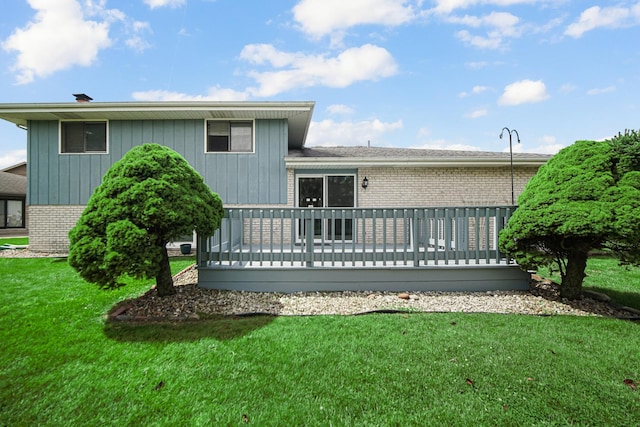 rear view of house featuring a wooden deck and a yard