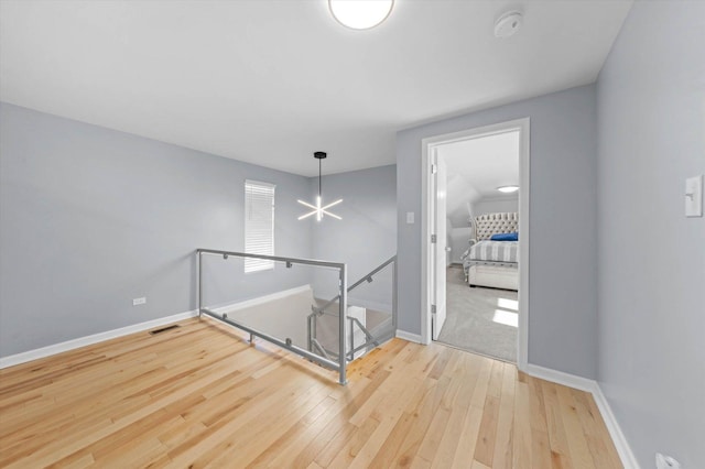 stairs with hardwood / wood-style floors and a notable chandelier