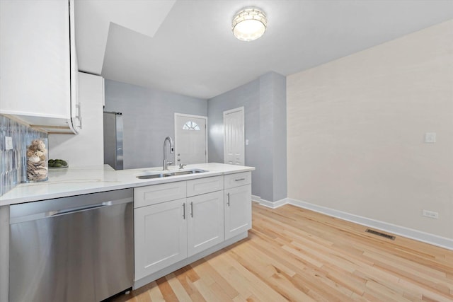 kitchen with sink, light stone counters, light hardwood / wood-style flooring, white cabinets, and appliances with stainless steel finishes