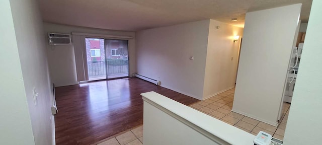 spare room featuring light hardwood / wood-style flooring, a wall mounted AC, and a baseboard heating unit