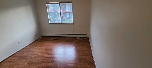 unfurnished room featuring dark hardwood / wood-style floors and baseboard heating