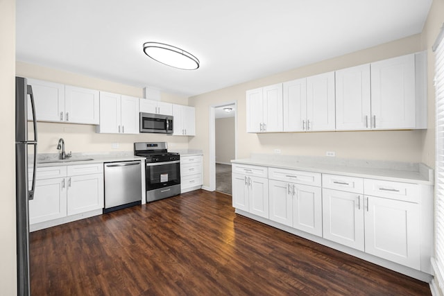 kitchen with stainless steel appliances, white cabinetry, and dark wood-type flooring