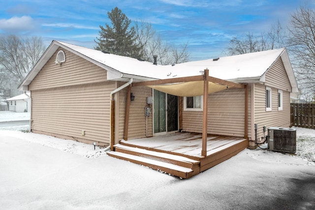 snow covered house with a deck and central air condition unit