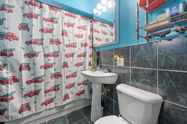 bathroom featuring tile patterned floors, shower / bath combo, tile walls, and toilet