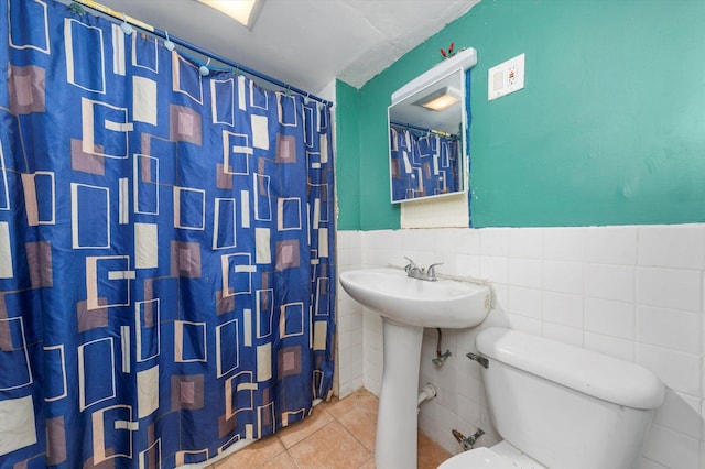 bathroom featuring sink, walk in shower, tile patterned floors, toilet, and tile walls