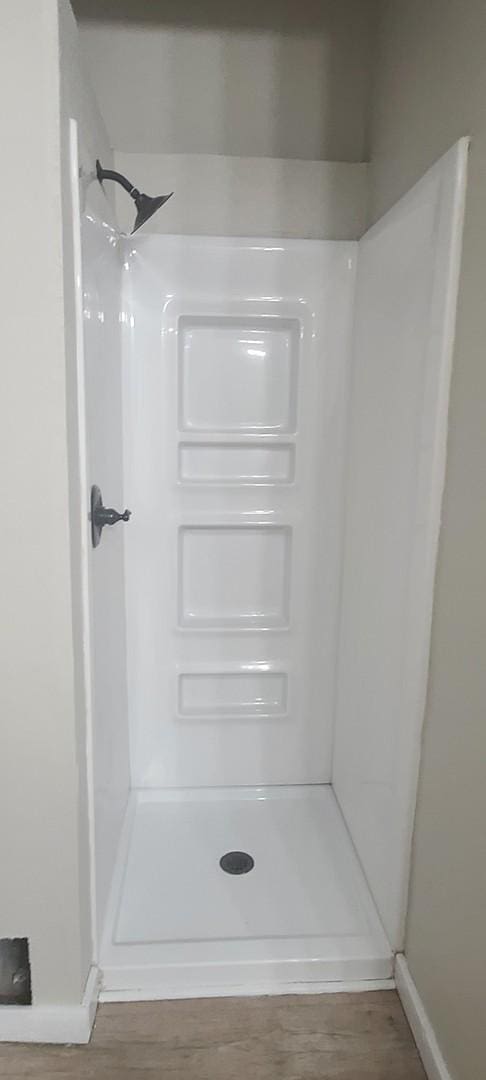 interior details featuring wood-type flooring and walk in shower