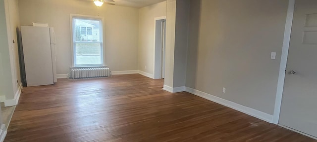 empty room featuring ceiling fan, radiator heating unit, and dark hardwood / wood-style floors