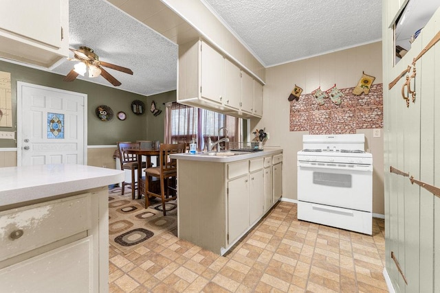 kitchen featuring a textured ceiling, white range oven, ceiling fan, sink, and white cabinets