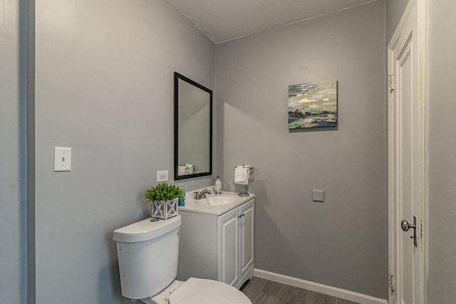 bathroom with hardwood / wood-style flooring, vanity, and toilet