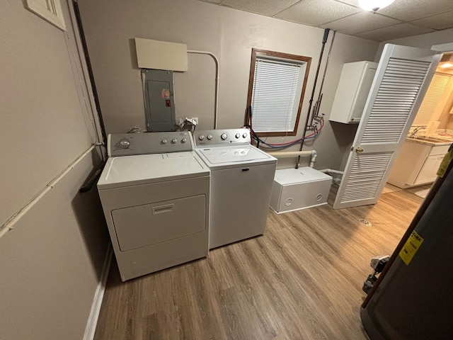 laundry area with washer and dryer, light hardwood / wood-style floors, cabinets, and electric panel