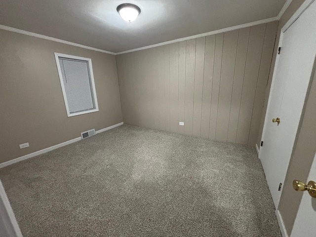 carpeted spare room featuring wooden walls and ornamental molding