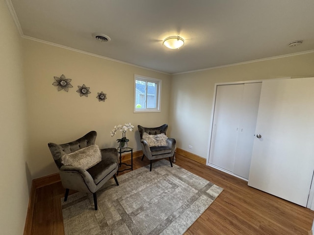 sitting room featuring wood-type flooring and ornamental molding