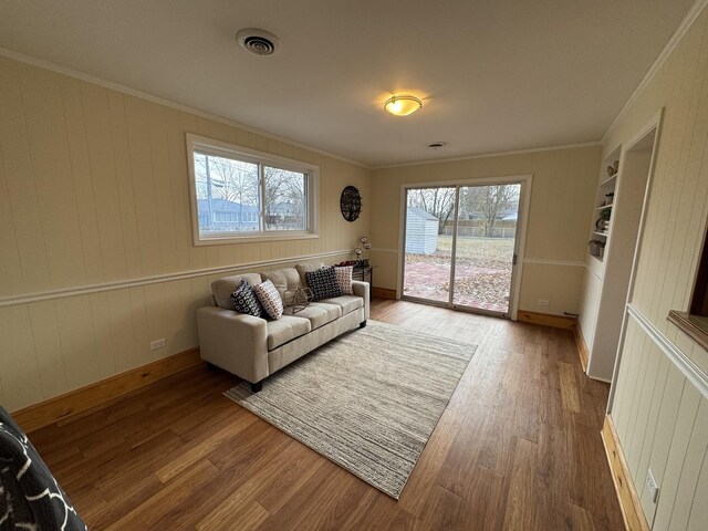 living room featuring wooden walls, hardwood / wood-style flooring, and crown molding