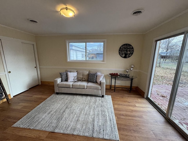 living room with hardwood / wood-style floors, plenty of natural light, and ornamental molding