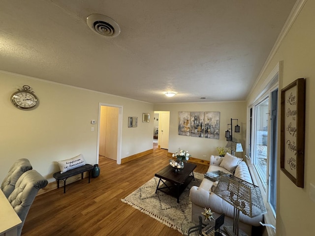 living room with wood-type flooring, a textured ceiling, and ornamental molding