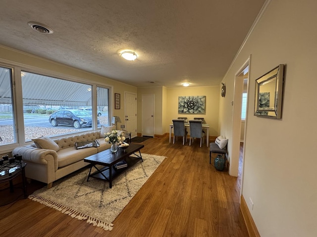 living room with hardwood / wood-style floors, plenty of natural light, ornamental molding, and a textured ceiling