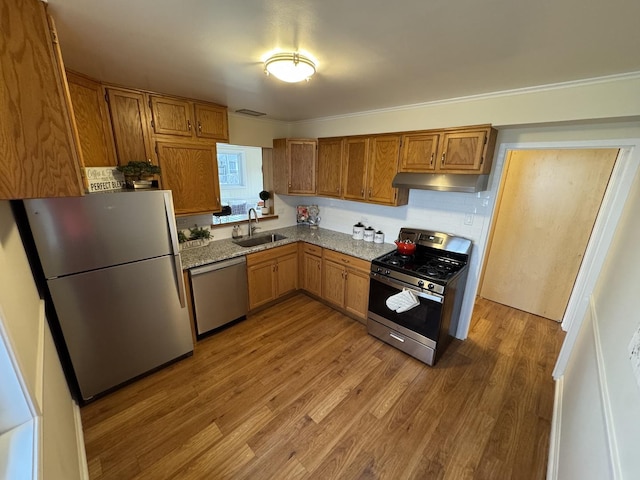 kitchen featuring sink, stainless steel appliances, hardwood / wood-style flooring, decorative backsplash, and ornamental molding