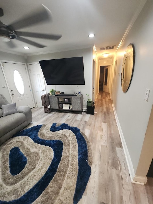 living room featuring hardwood / wood-style floors, ceiling fan, and crown molding