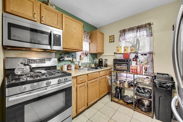 kitchen with appliances with stainless steel finishes, light tile patterned floors, and sink