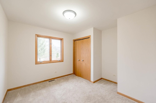 unfurnished bedroom featuring light colored carpet and a closet