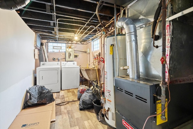 basement featuring electric panel, gas water heater, sink, washing machine and dryer, and wood-type flooring