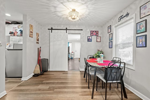 dining space featuring a barn door and hardwood / wood-style flooring