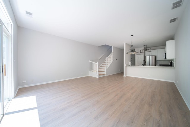 unfurnished living room with light hardwood / wood-style flooring and sink