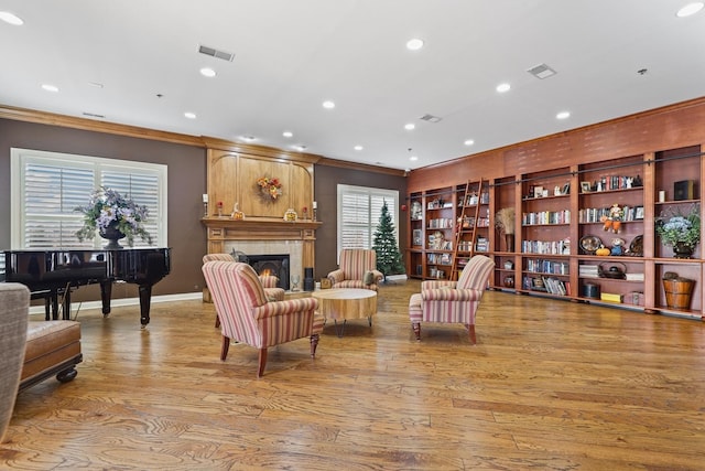 sitting room featuring crown molding, a fireplace, and light hardwood / wood-style floors