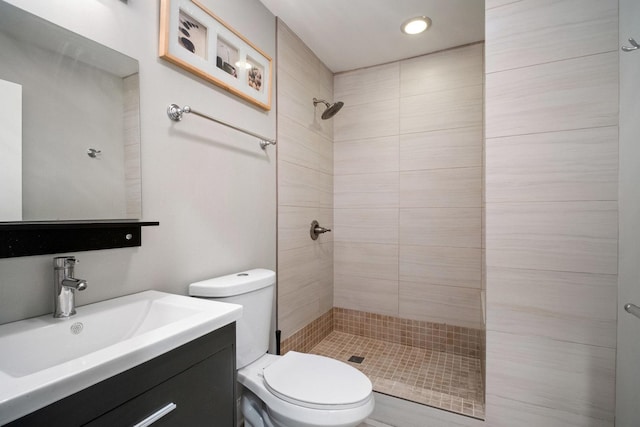 bathroom featuring a tile shower, vanity, and toilet