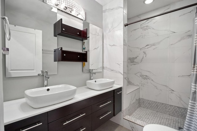 bathroom with toilet, vanity, and tiled shower