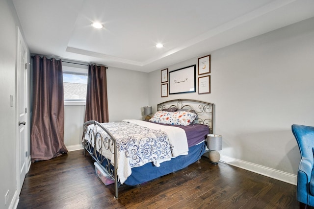 bedroom with a tray ceiling and dark hardwood / wood-style flooring