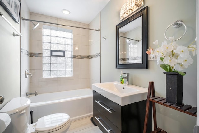 full bathroom featuring vanity, hardwood / wood-style floors, tiled shower / bath, and toilet