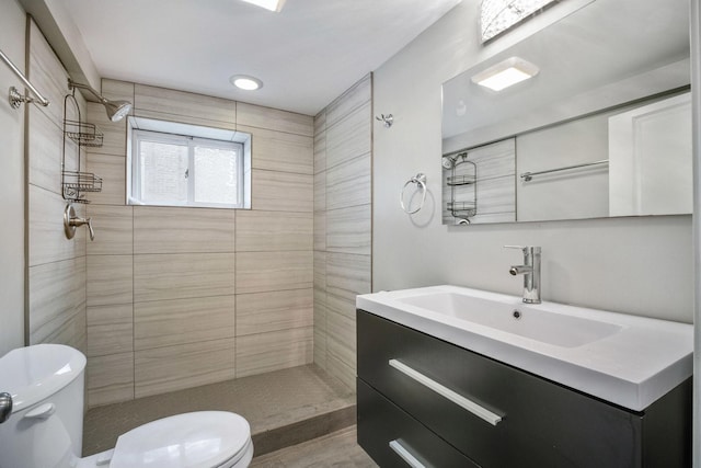 bathroom featuring tiled shower, wood-type flooring, vanity, and toilet