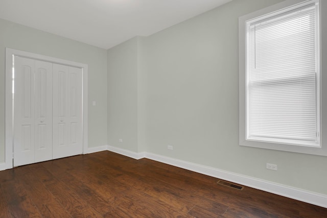 unfurnished bedroom with dark hardwood / wood-style flooring and a closet