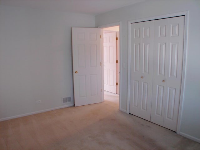 unfurnished bedroom with light carpet and a closet