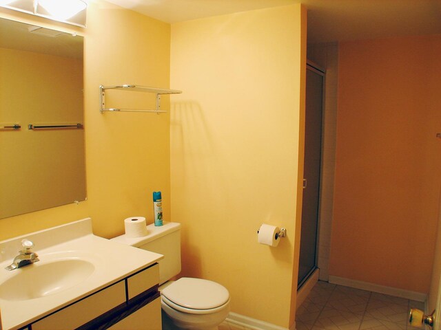 bathroom with tile patterned flooring, vanity, toilet, and a shower with door