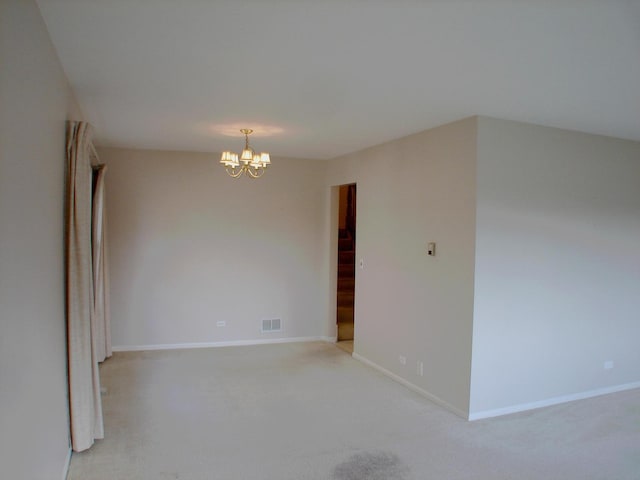 carpeted empty room with a notable chandelier