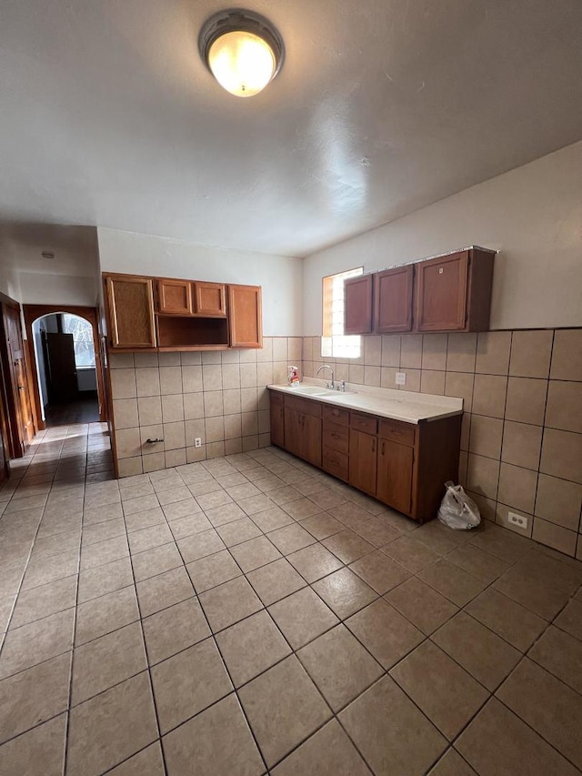 kitchen with tile patterned floors, sink, and tile walls