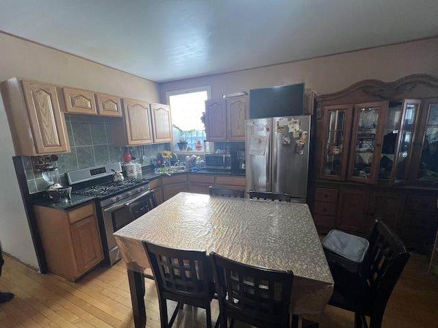 kitchen with appliances with stainless steel finishes, backsplash, light hardwood / wood-style flooring, and light brown cabinets