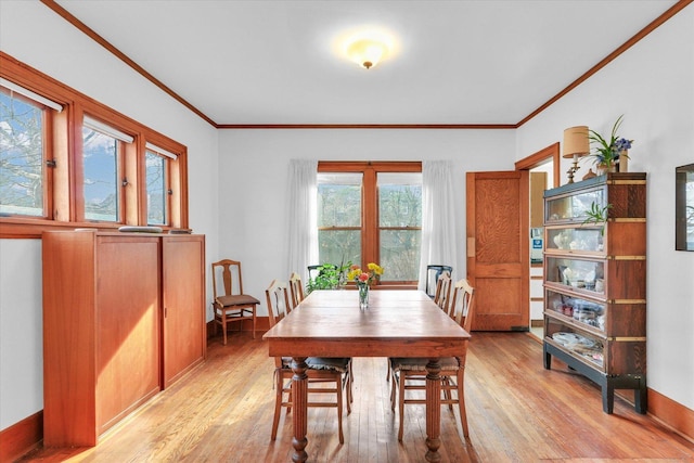 dining space with crown molding and light hardwood / wood-style flooring