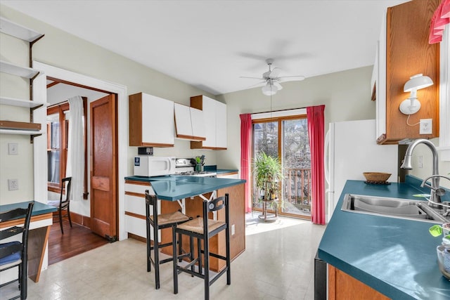 kitchen with stove, sink, white cabinets, and ceiling fan